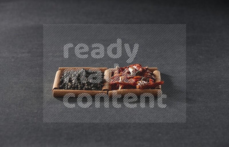 2 squares of cinnamon sticks full of chilis and black peppers on black flooring