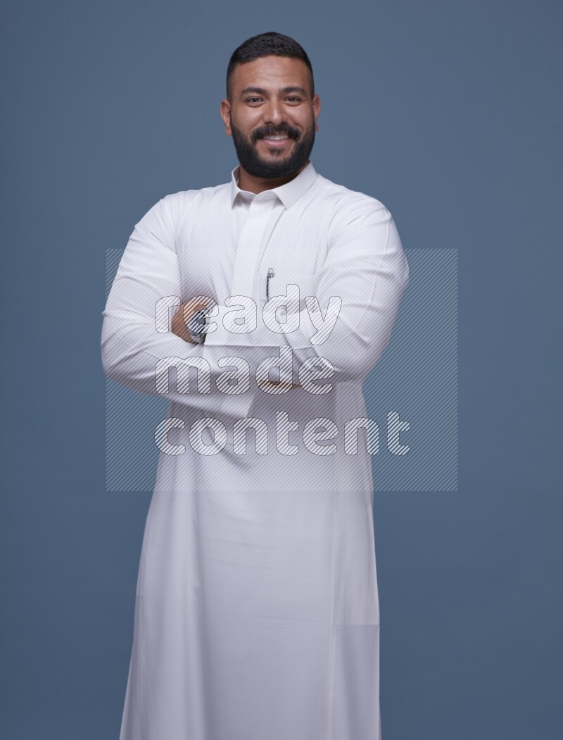 A man Posing in Blue Background wearing a Saudi Thob