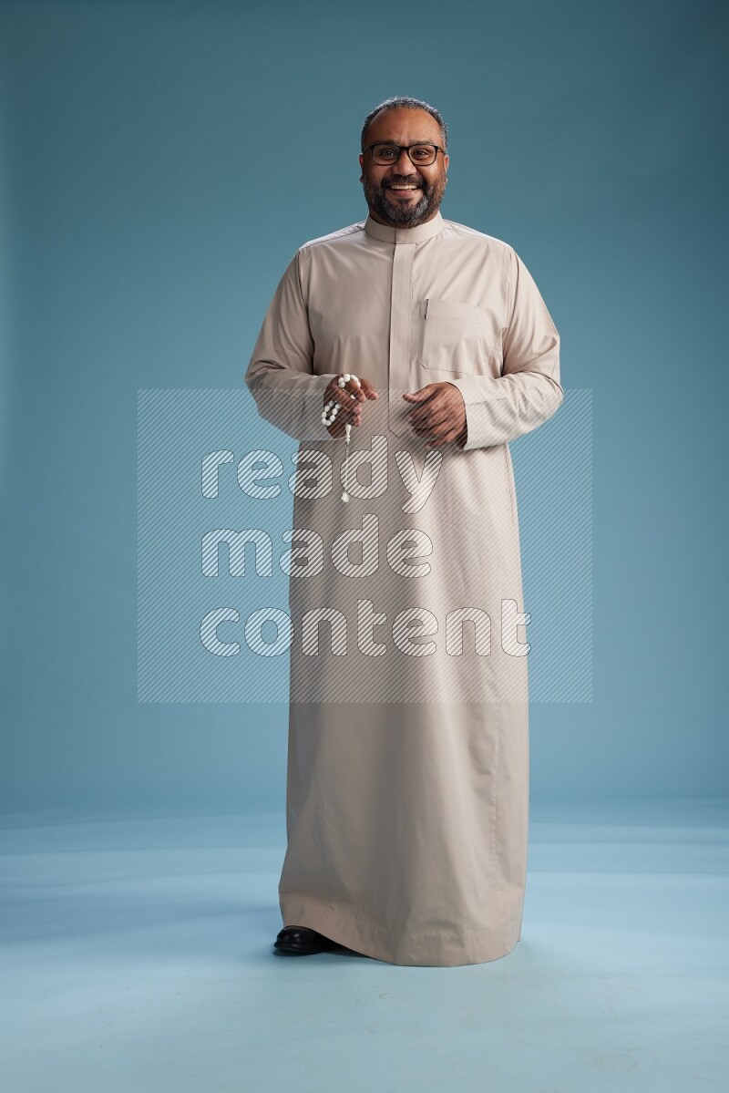 Saudi Man without shimag Standing Interacting with the camera on blue background