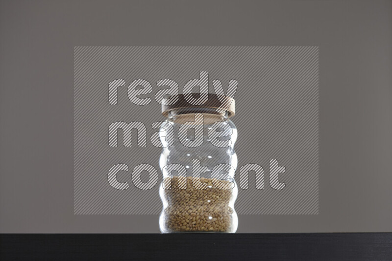 Hulled wheat in a glass jar on black background
