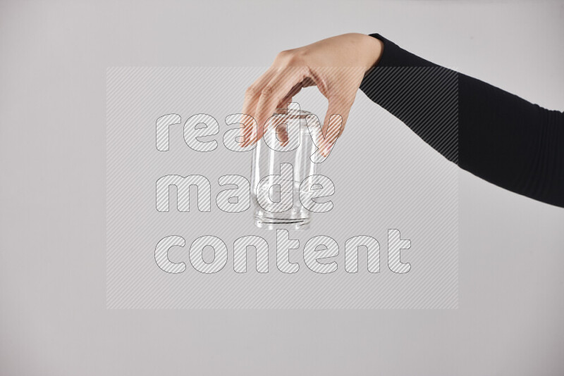 A woman in black abaya holding different glassware in different positions