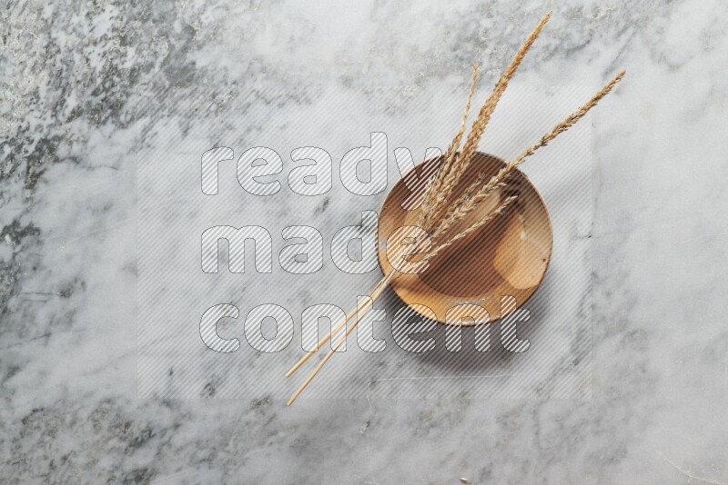 Wheat stalks on multicolored pottery plate on grey marble background