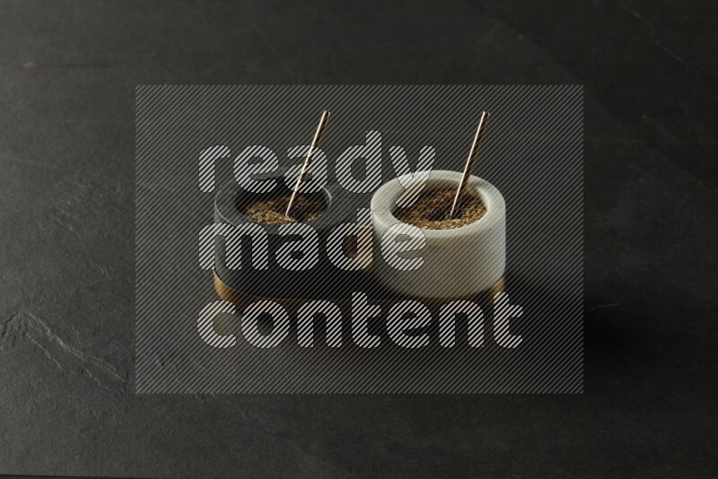 black and white round marble containers filled with herbs on gray textured countertop