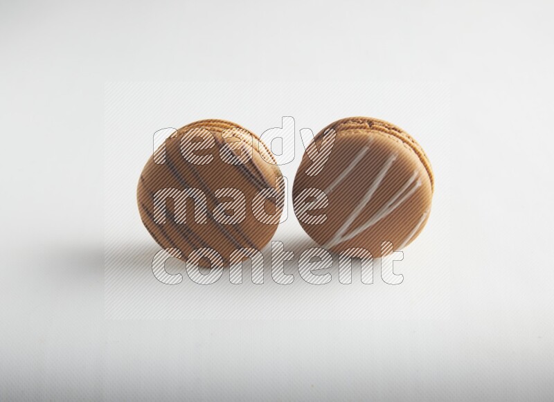45º Shot of of two assorted Brown Irish Cream, and light brown  Almond Cream macarons on white background