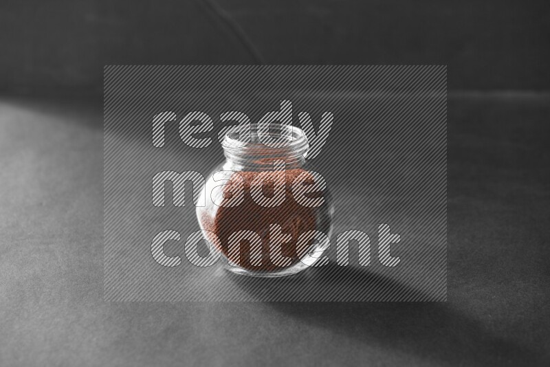 A glass spice jar full of garden cress on black flooring