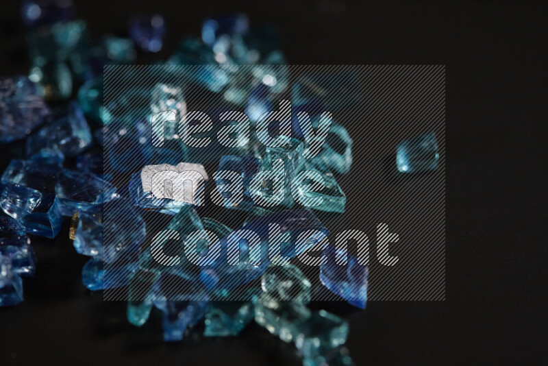 Transparent blue fragments of glass scattered on a black background