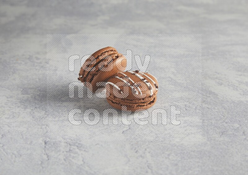 45º Shot of two Brown white marbleChocolate Caramel macarons  on white  marble background
