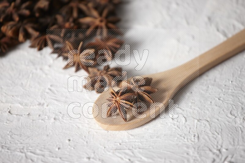 Star anise on a wooden spoon and spreading on the background on a white flooring