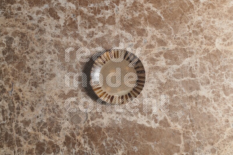 A multicolored pottery plate on beige marble background
