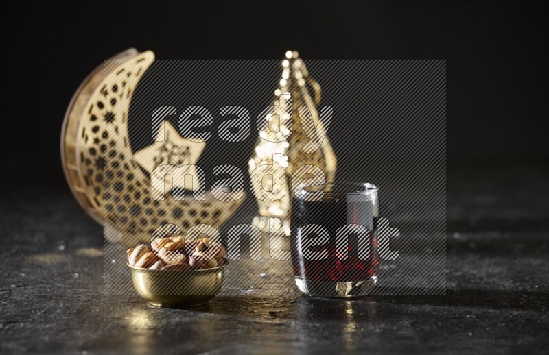 Nuts in a metal bowl with tamarind beside golden lanterns in a dark setup