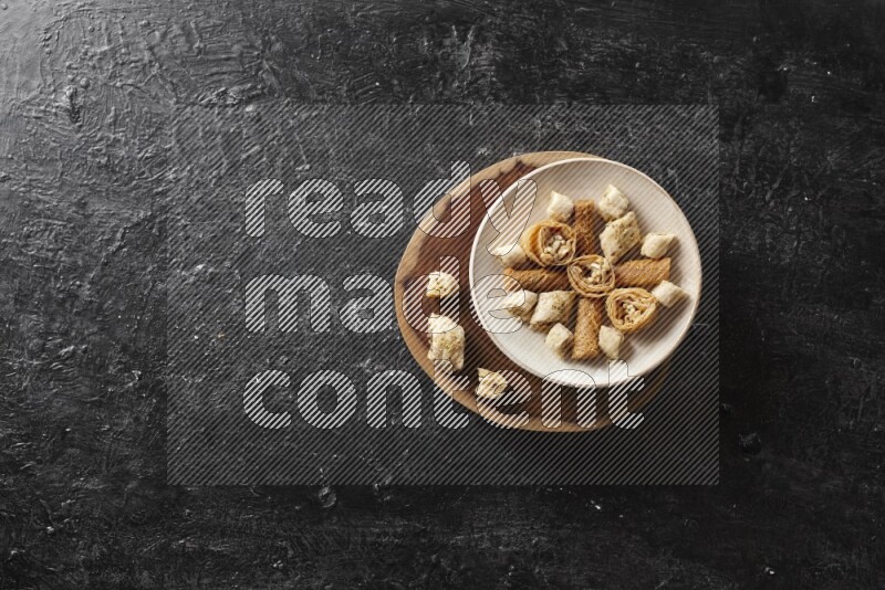 حلويات شرقية في أطباق فخارية علي خلفية سوداء خشبية