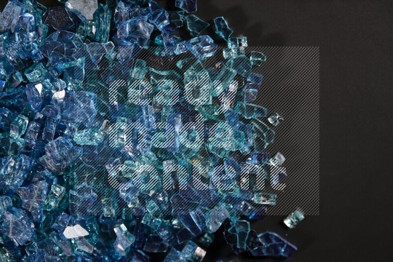 Transparent blue fragments of glass scattered on a black background