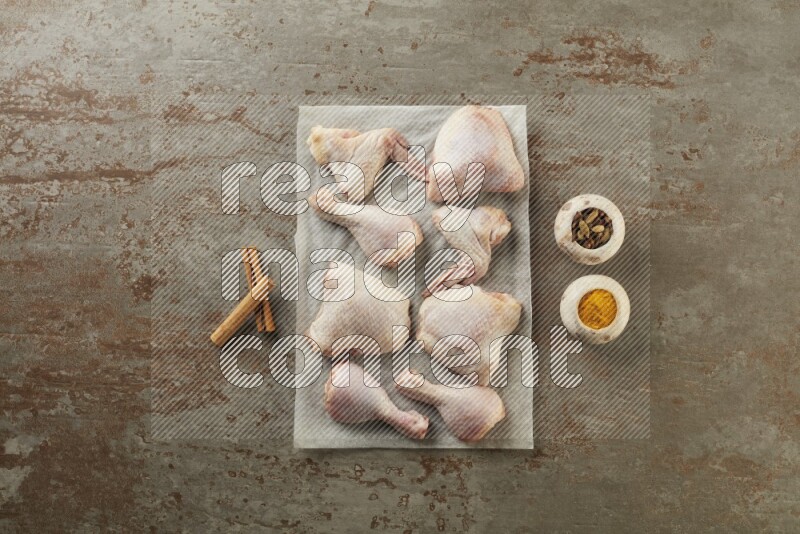 Mixed fresh chicken pieces on a parchment paper direct on a textured rustic background