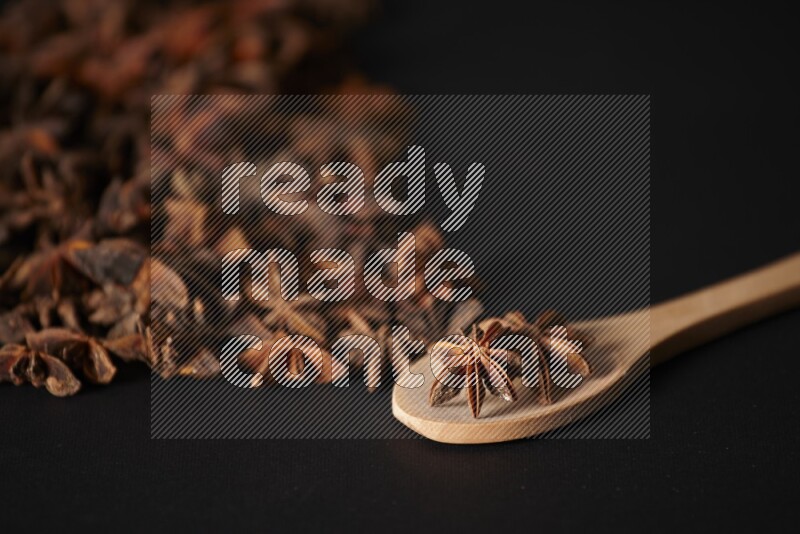 Star Anise in a wooden spoon and spreading on a black flooring
