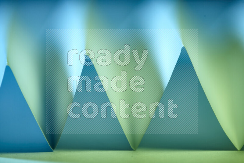 صورة مجردة مقربة تظهر طيات ورقية هندسية حادة بتدرجات اللون الأخضر والأزرق