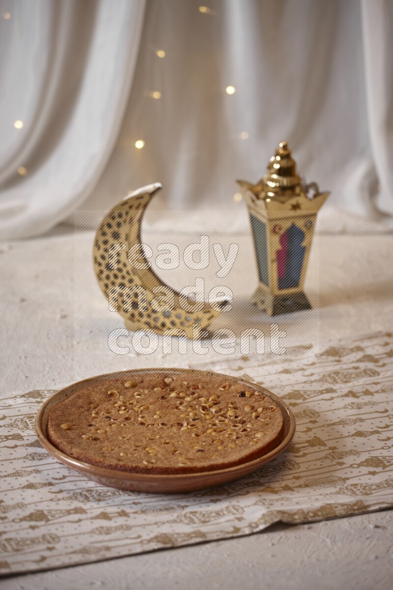 صحن من البسبوسة بجانب فوانيس علي خلفية بيضاء خشبية