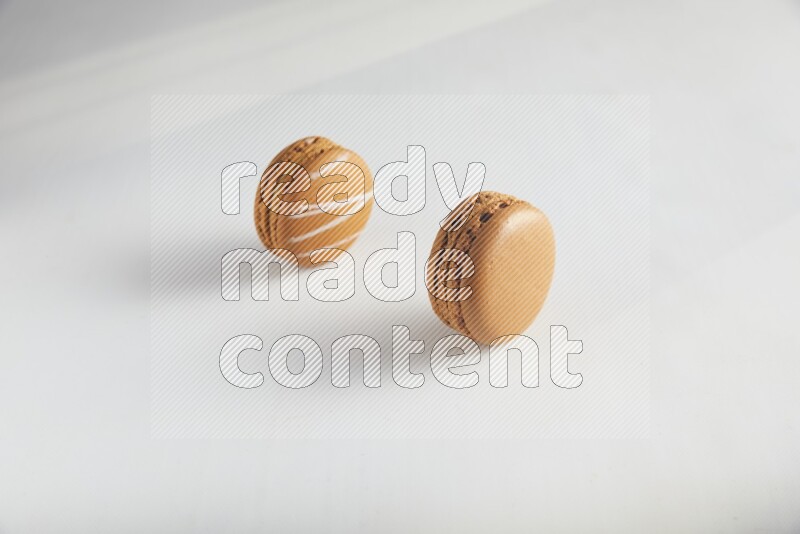 45º Shot of of two assorted Brown Irish Cream, and Brown Maple Taffy macarons  on white background