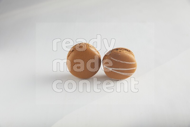 45º Shot of of two assorted Brown Irish Cream, and Brown Maple Taffy macarons  on white background