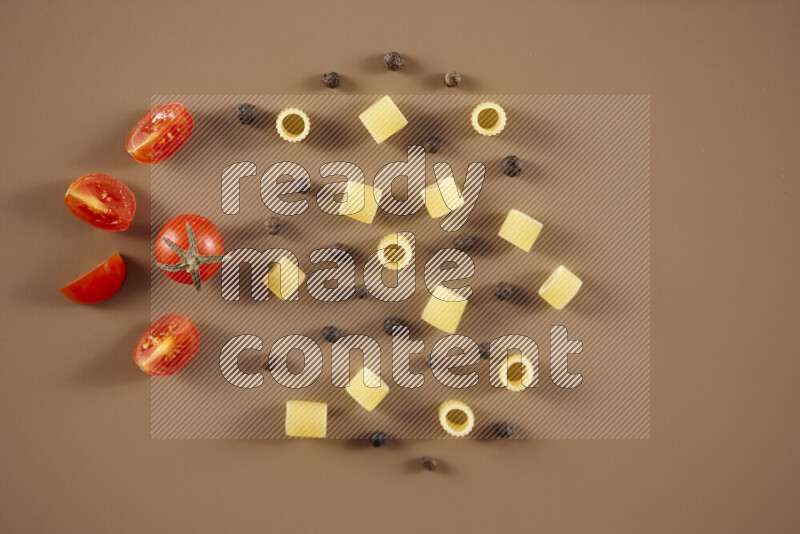 Raw pasta with different ingredients such as cherry tomatoes, garlic, onions, red chilis, black pepper, white pepper, bay laurel leaves, rosemary and cardamom on beige background