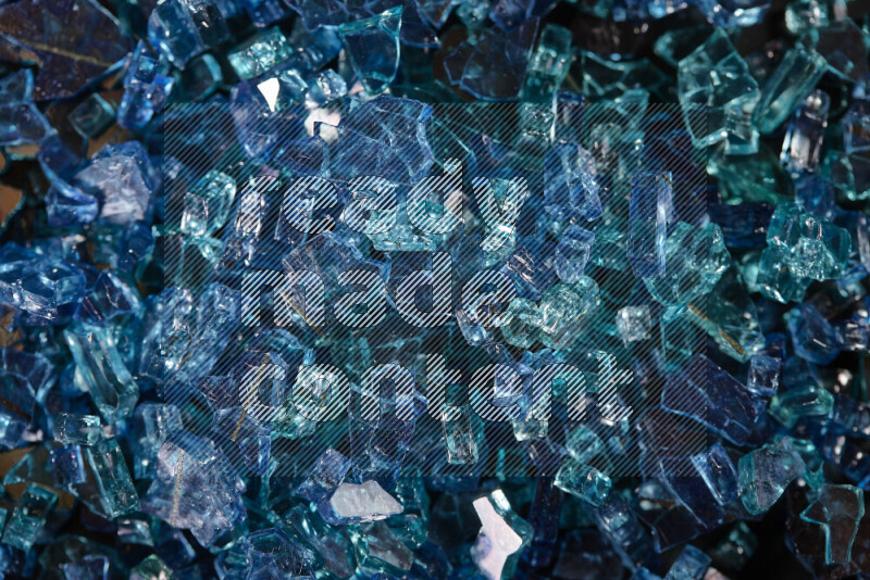 Transparent blue fragments of glass scattered on a black background
