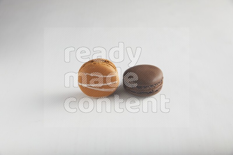 45º Shot of of two assorted Brown Irish Cream, and Brown Dark Chocolate macarons on white background