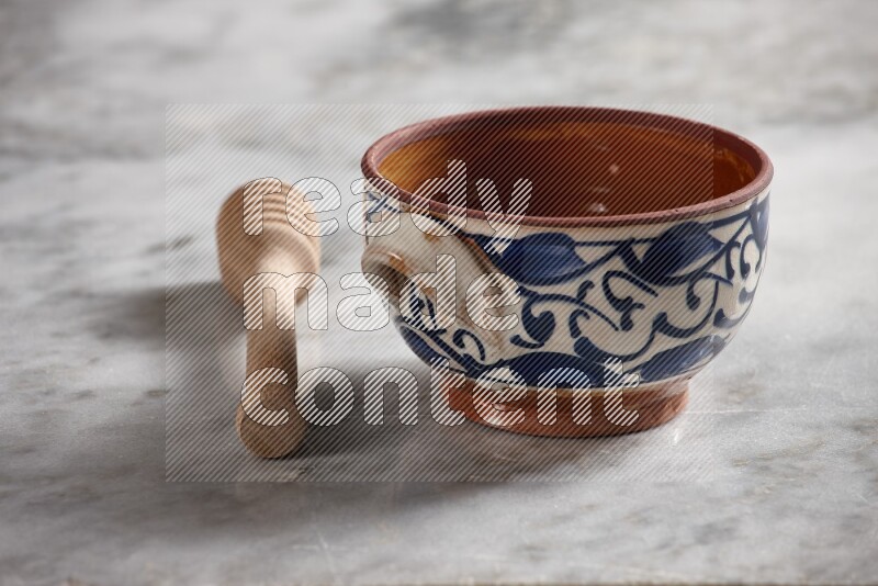 Decorative pottery pot with wooden honey dipper on the side on grey marble background