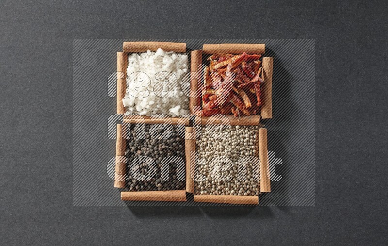 4 squares of cinnamon sticks full of black pepper, white pepper, dried red chilis and white salt on black flooring