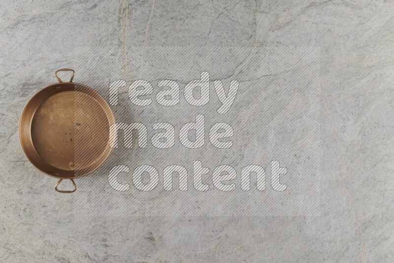 A small copper pan on grey marble background