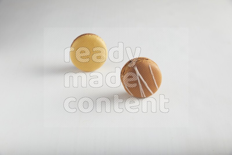 45º Shot of of two assorted Brown Irish Cream, and Yellow, and Brown Chai Latte macarons on white background
