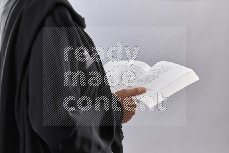 A woman in abaya holding books and a board in different positions (back to school)