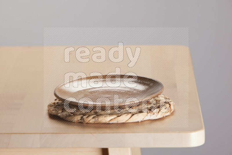 multi-colored pottery Plate placed on a small light colored straw placemat on the edge of wooden table
