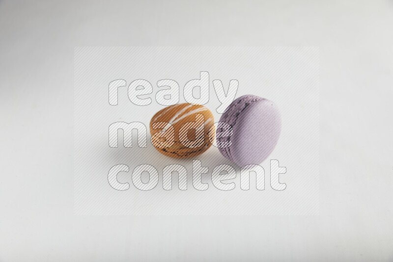 45º Shot of of two assorted Brown Irish Cream, and Purple Blueberry macarons on white background