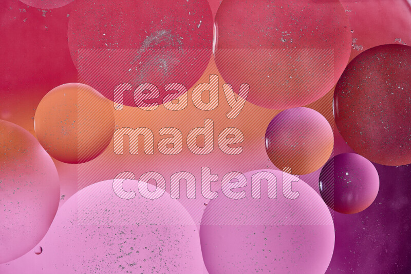 Close-ups of abstract oil bubbles on water surface in shades of red, orange and pink