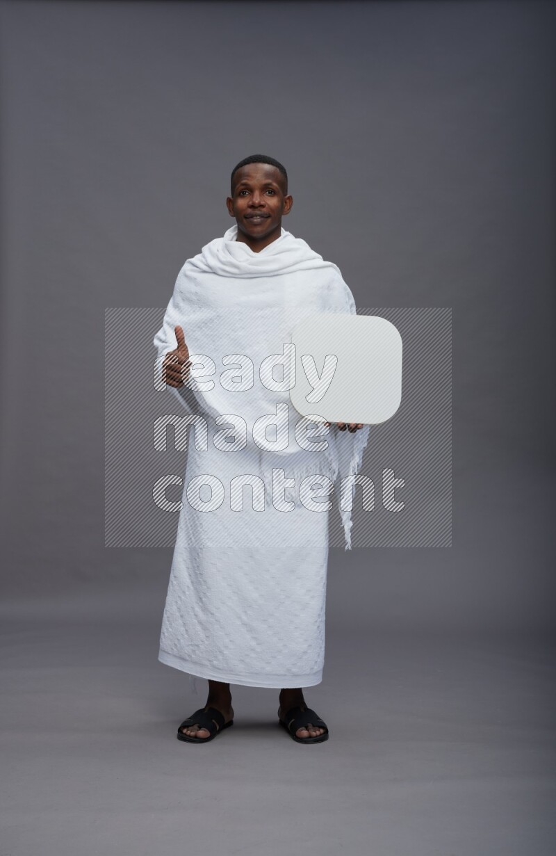 A man wearing Ehram Standing holding social media sign on gray background