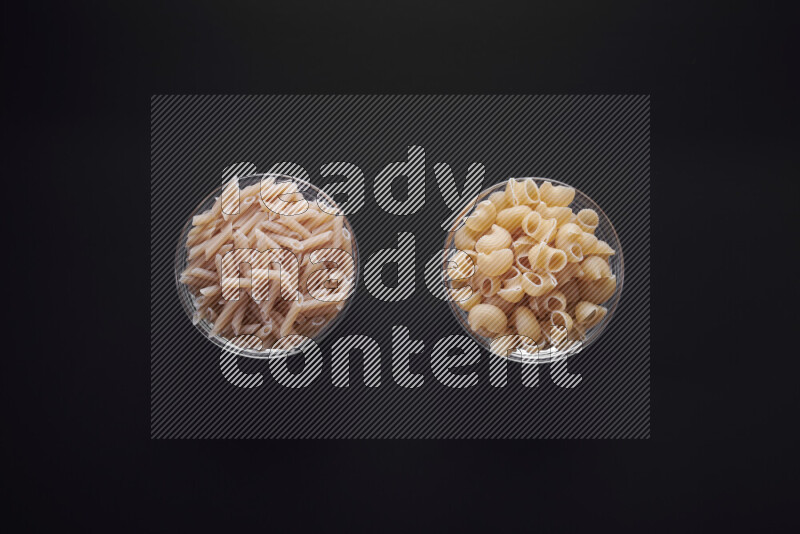 Different pasta types in glass bowls on black background