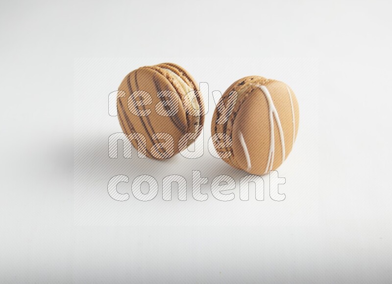 45º Shot of of two assorted Brown Irish Cream, and light brown  Almond Cream macarons on white background