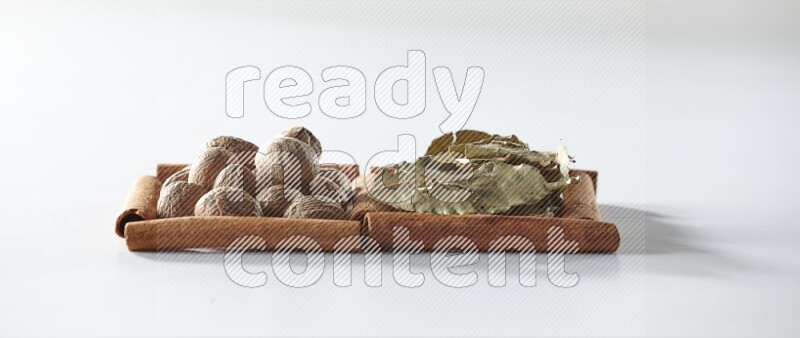 2 squares of cinnamon sticks full of bay laurel leaves and nutmegs on white flooring