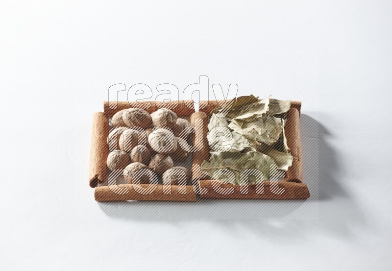 2 squares of cinnamon sticks full of bay laurel leaves and nutmegs on white flooring