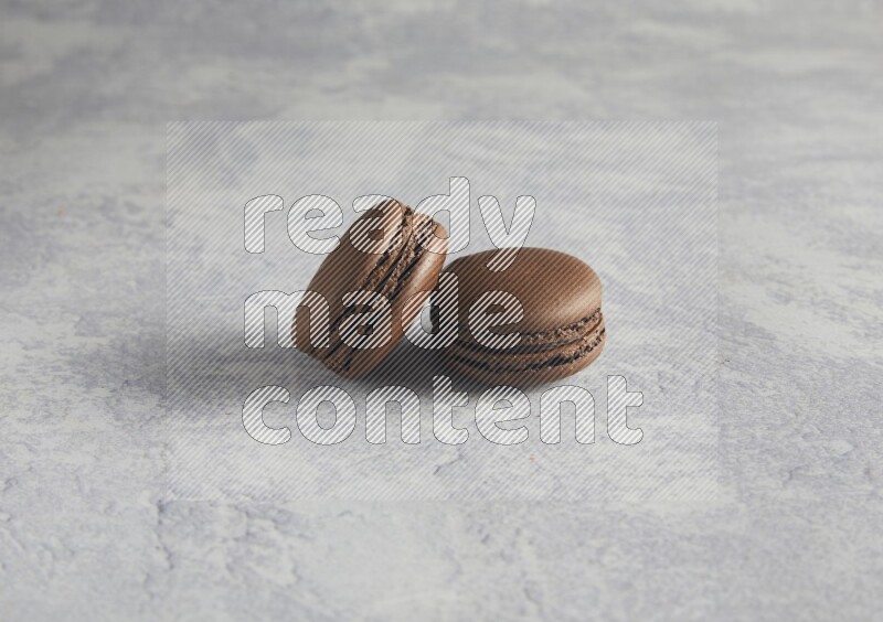 45º Shot of two Brown Dark Chocolate macarons  on white  marble background