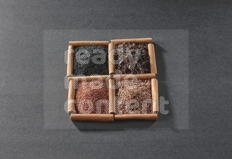 4 squares of cinnamon sticks full of black seeds, garden cress, flaxseeds and cloves on black flooring