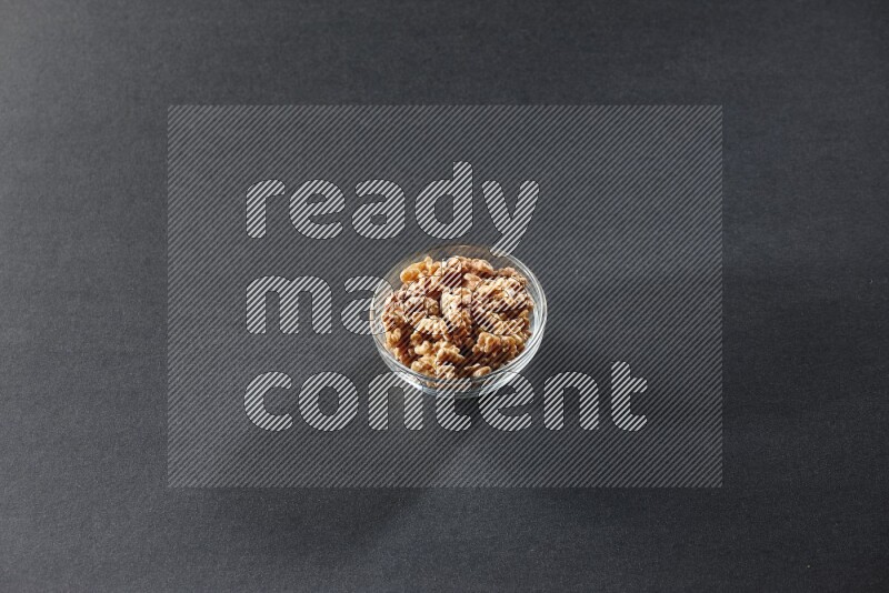 A glass bowl full of peeled walnuts on a black background in different angles