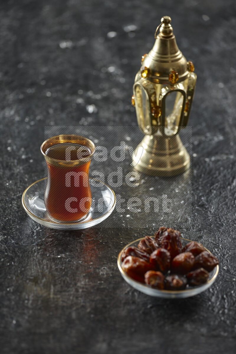A golden lantern with different drinks, dates, nuts, prayer beads and quran on textured black background