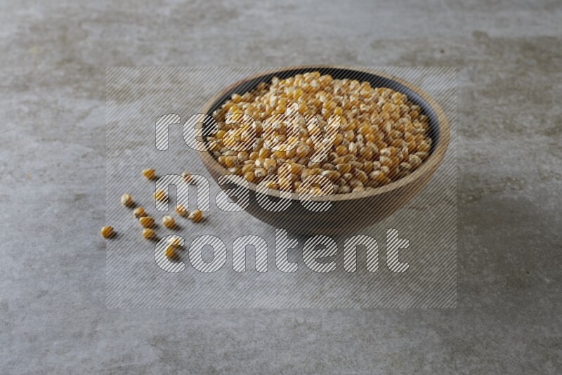 corn kernel in a wooden bowl on a grey textured countertop