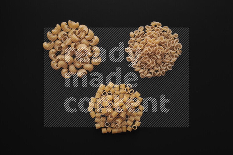 Different pasta types in bunches on black background