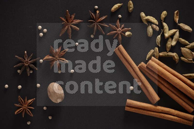 Cinnamon sticks, cardamom, star anise, nutmeg and white peppers on a black background