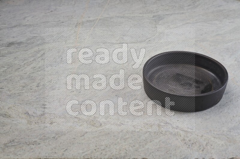 وعاء فرن فخاري أسود على خلفية من الرخام الرمادي