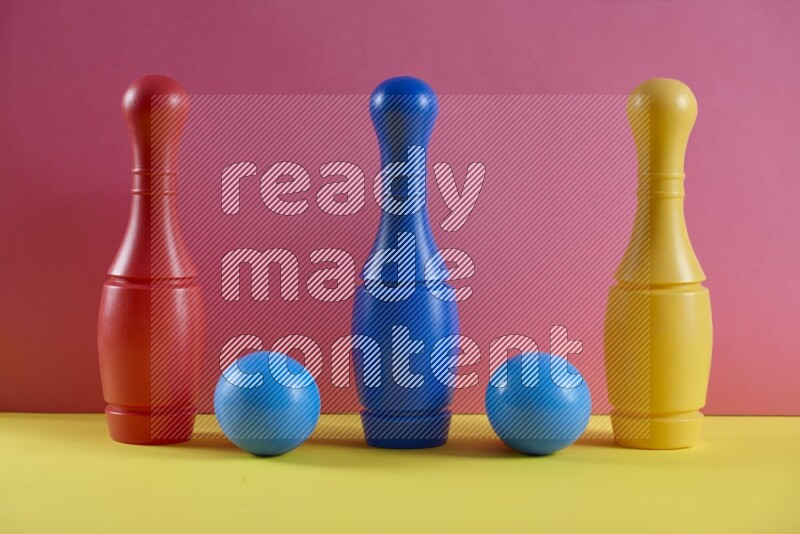 Plastic bowling pins with balls on pink and yellow background (kids toys)