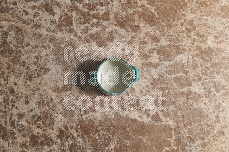 A multicolored pottery bowl on beige marble background
