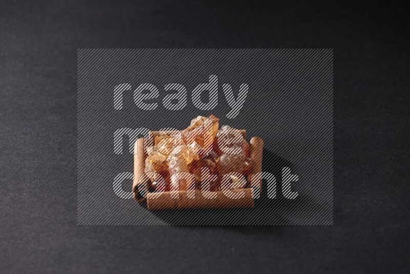 A single square of cinnamon sticks full of Arabic gum on black flooring