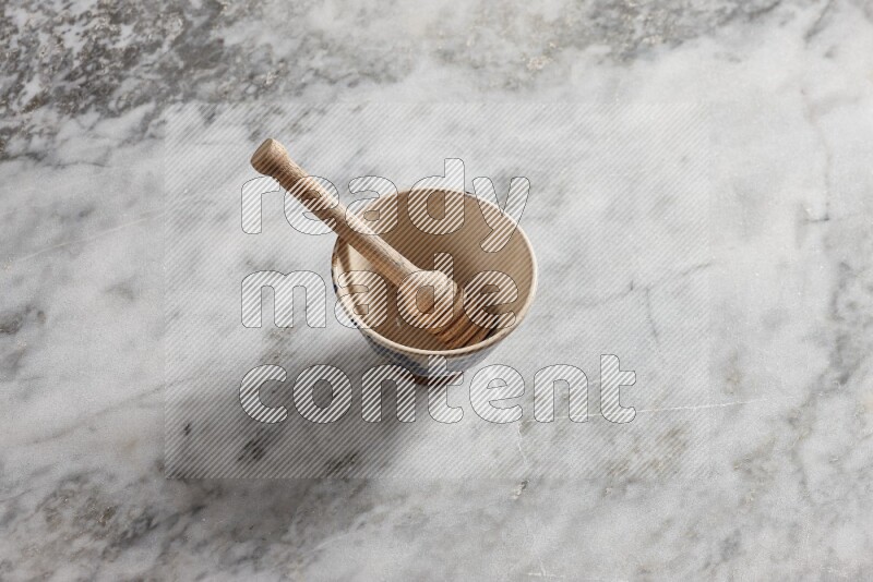 Beige pottery bowl with wooden honey dipper in it on grey marble background